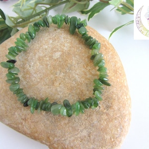 Peut inclure: Un bracelet en pierres de jade vert sur un rocher brun clair. Le bracelet est composé de petites pierres de jade de forme irrégulière.