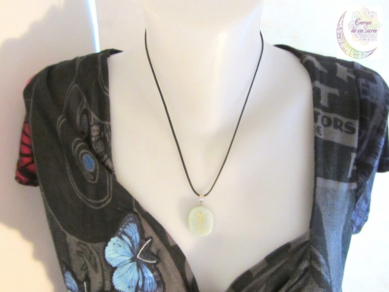 May include: A light green stone pendant necklace with a black cord. The pendant is round and has a smooth, polished surface.
