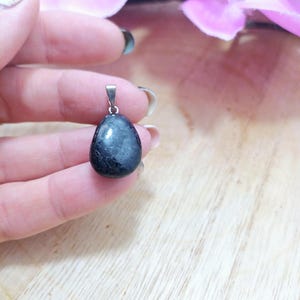 K&ouml;nnte beinhalten: Ein schwarzer Edelstein-Anh&auml;nger mit einer silbernen &Ouml;se. Der Edelstein ist oval geformt und hat eine glatte, polierte Oberfl&auml;che.