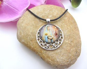 May include: A silver necklace with a round pendant featuring a religious image of Mary holding baby Jesus. The pendant is surrounded by a circle of stars.