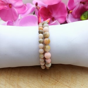 May include: A double-strand bracelet made of pink, white, and brown gemstone beads. The bracelet is on a white surface.