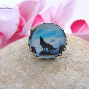 Könnte beinhalten: Ein silberner Ring mit einem Glas-Cameo, das einen schwarzen Wolf zeigt, der zum Mond heult. Der Cameo hat einen blauen und weißen, bewölkten Himmelshintergrund.