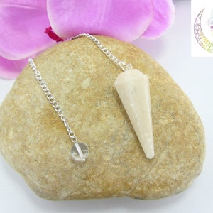 Può includere: Un pendolo di cristallo bianco con una catena d'argento. Il pendolo è appoggiato su una roccia marrone.