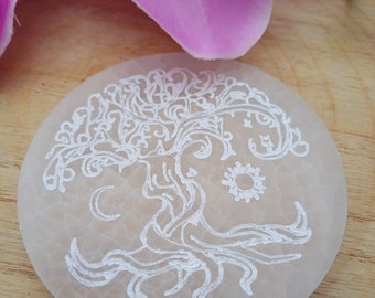 May include: White selenite stone with a white tree of life design etched into the surface. The stone is round and has a smooth, polished finish.
