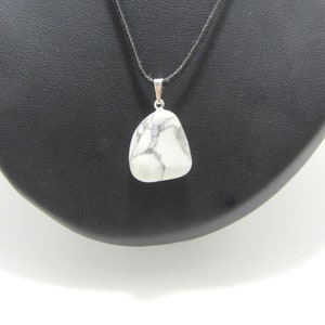 May include: A white howlite pendant necklace with a black cord. The pendant is a natural stone with gray veining.