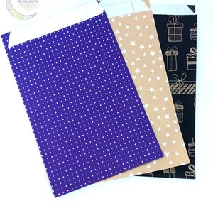 May include: Three rectangular paper envelopes with white adhesive flaps. The first is purple with a white polka dot pattern. The second is tan with a white star pattern. The third is black with a white line drawing pattern of gift boxes.