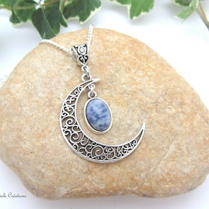 Peut inclure: Un collier avec un pendentif en forme de croissant de lune argenté orné d'une pierre précieuse bleue et blanche. Le pendentif est sur une chaîne en argent.