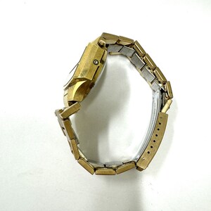 May include: A gold-toned wristwatch with a square face and a metal band. The watch is on a white background.