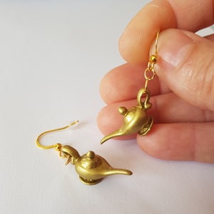 May include: Gold-toned genie lamp earrings with a hook fastening. The lamps are detailed with a spout and a knob on top.