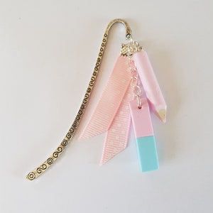 May include: A silver bookmark with a pink ribbon and two pink and blue eraser charms.
