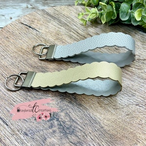 May include: Two keychains with scalloped edges. One is silver and the other is gold. Both have a silver key ring.