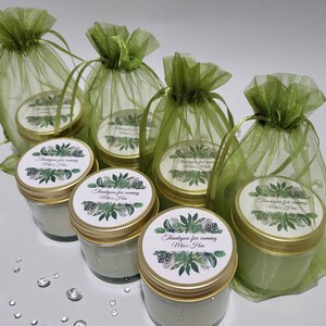 Puede incluir: Seis peque&ntilde;os frascos de vidrio con tapas doradas y etiquetas verdes y blancas que dicen "Gracias por venir Mia's Hen". Los frascos est&aacute;n en bolsas de organza verde.