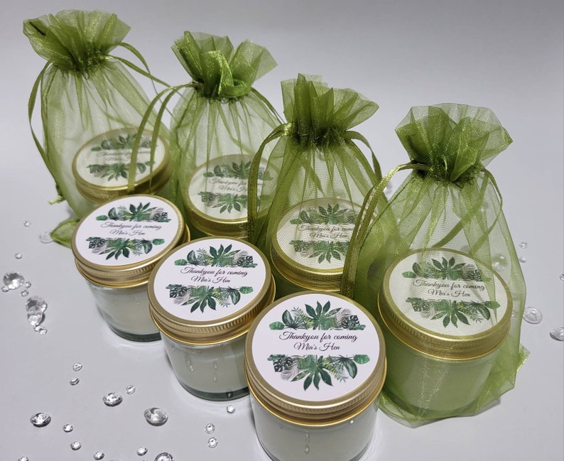 Puede incluir: Seis peque&ntilde;os frascos de vidrio con tapas doradas y etiquetas verdes y blancas que dicen "Gracias por venir Mia's Hen". Los frascos est&aacute;n en bolsas de organza verde.