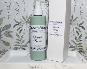 May include: A light green room spray bottle and matching white box. The bottle and box have labels that read "ELISEWAX Oriental Musk" with floral accents. The spray bottle is on a white tray with a marble design.