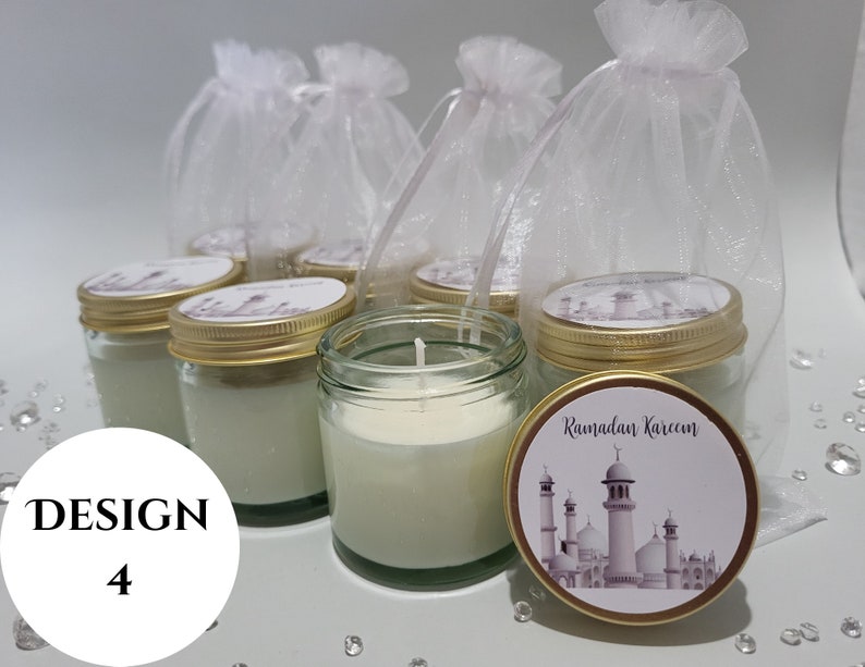 May include: Set of six small glass jars with gold lids and white candles. Each jar has a white label with a mosque design and the text "Ramadan Kareem". The jars are displayed on a white surface with white tulle bags.