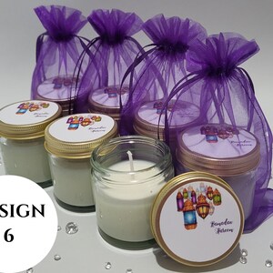 May include: Six small glass jars with gold lids and labels that say "Ramadan Kareem" in a decorative font. The jars are filled with white candles and are sitting on a purple sheer fabric.