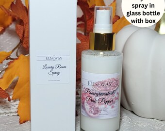 May include: A 100ml luxury room spray in a glass bottle with a gold cap and a white box. The label reads "ELISEWAX Pomegranate & Pink Pepper". The box has the text "ELISEWAX Luxury Room Spray".