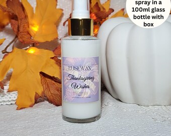 May include: A 100 ml glass bottle of room spray with a gold lid and a purple label that says "Elisewax Thanksgiving Wishes". The bottle is sitting on a white surface with fall leaves and a white pumpkin.