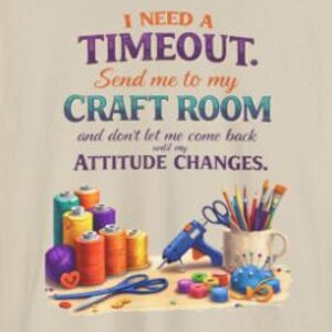 May include: A beige t-shirt with the text "I NEED A TIMEOUT. Send me to my CRAFT ROOM and don't let me come back until my ATTITUDE CHANGES." The image includes spools of thread, scissors, a glue gun, and paintbrushes.