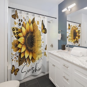 May include: A white shower curtain with a large sunflower design in yellow and brown, decorated with butterflies and leopard print. The text "When you can't find the sunshine, be sunshine" is written in script.