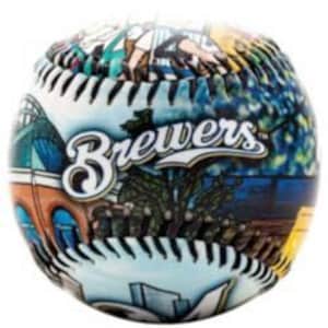 May include: A baseball with a colorful design featuring the word "Brewers" in white script. The ball has a detailed illustration of a stadium and other imagery. The stitching is black and the background is white.