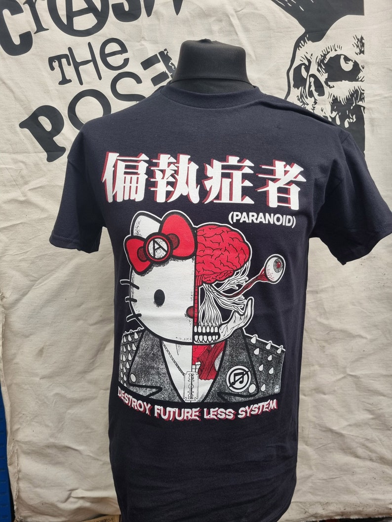 May include: Black t-shirt with a graphic of a Hello Kitty character with a skull and brain on the right side of its face. The graphic also includes the text "Paranoid" and "Destroy Future Less System".