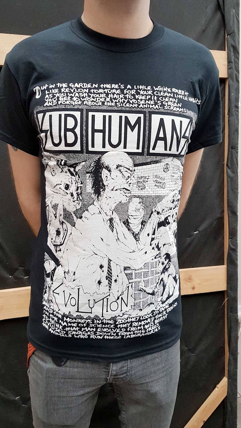 May include: Black t-shirt with a white graphic print of a band called "Sub Humans" and the text "Evolution". The graphic features a man with a cat and a building with the text "Anarchy" on it.
