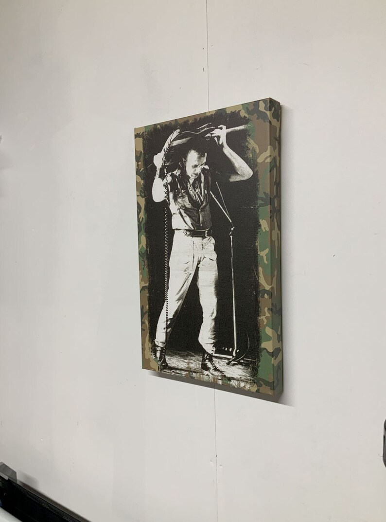 Op de afbeelding: Een zwart-witfoto van een muzikant die op het podium optreedt. De foto is afgedrukt op een canvas met een camouflage rand.