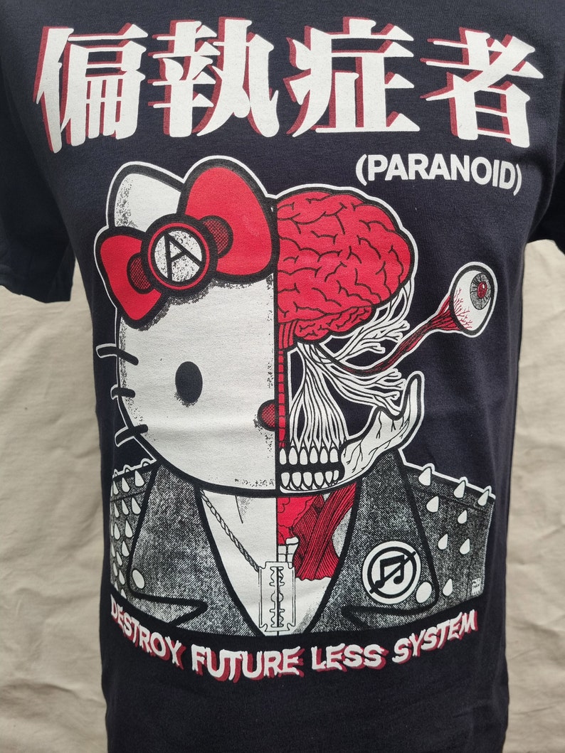 May include: Black t-shirt with a white graphic of a Hello Kitty character with a skull and brain on the right side of its face. The graphic also includes a razor blade, a chain, and the text "Destroy Future Less System". The text "Paranoid" is printed in white above the graphic.