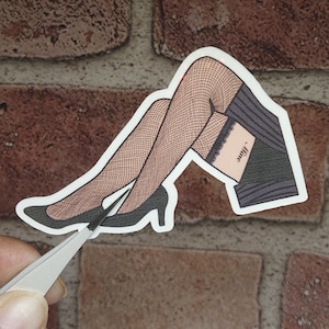 May include: A sticker of a woman's legs wearing black fishnet stockings and high heels. The sticker has a black and white striped skirt and the text "'Just'" on the thigh.