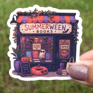 May include: A die-cut sticker featuring a bookstore storefront with a purple and orange striped awning, labeled Summerween Books. The display window shows a ghost wearing sunglasses, books, a pumpkin, and an orange inflatable pool ring.
