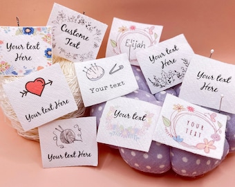Puede incluir: Diez cuadrados de tela blanca con diferentes diseños y el texto "Your text here" impreso en cada uno. Los diseños incluyen un corazón con una flecha, una aguja de coser y hilo, una madeja de hilo, una corona de flores y un patrón floral.