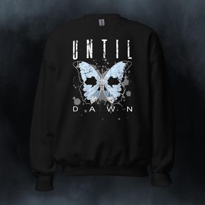 Peut inclure: Sweat-shirt noir avec un motif de papillon blanc et le texte "UNTIL DAWN" imprimé sur le devant.