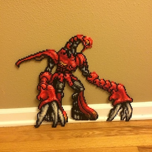May include: A red and black pixel art figure of a creature with a long tail and claws. The figure is made of small plastic beads and is displayed on a wall.