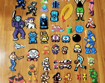 Peut inclure: Une collection de plus de 50 personnages de jeux vidéo classiques en pixel art, réalisés avec des perles Perler colorées. Les personnages incluent Mario, Luigi, Donkey Kong, Pac-Man, et bien d'autres.