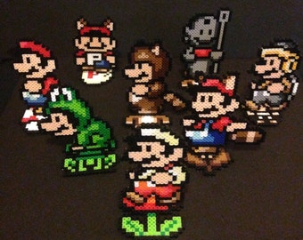 May include: A collection of eight pixel art characters from the Super Mario Bros. video game series. The characters are made of colorful beads and include Mario, Luigi, Toad, Princess Peach, Bowser, and Yoshi.