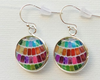 Puede incluir: Un par de pendientes de plata con colgantes redondos de estilo mosaico de colores. El diseño de mosaico presenta una variedad de colores, incluyendo rojo, naranja, amarillo, verde, azul, morado y rosa.