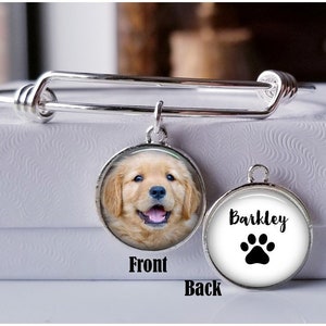 May include: Silver expandable bracelet with a charm featuring a photo of a golden retriever puppy on the front and the name "Barkley" and a paw print on the back.