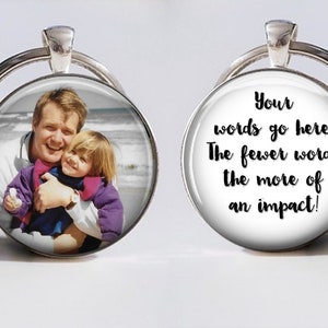 May include: A silver keychain with a round glass charm. The charm has a photo of a father and daughter on the beach. The other side of the charm has the text "Your words go here. The fewer words the more of an impact!"