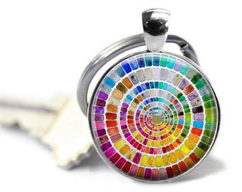 May include: A silver key chain with a round glass charm featuring a colorful watercolor paint color wheel design.