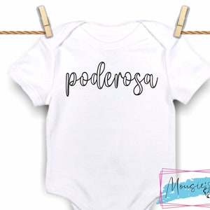 May include: White baby onesie with the word "poderosa" written in black cursive script.
