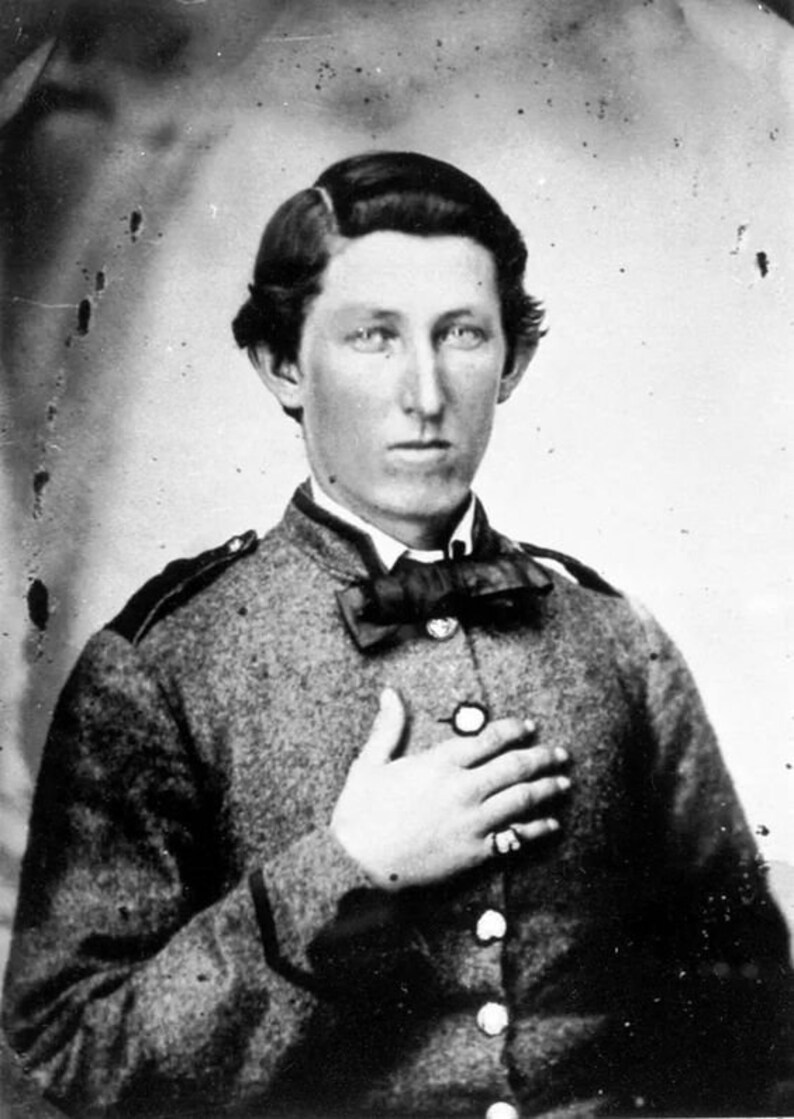 Puede incluir: Retrato en blanco y negro de un joven con uniforme militar y corbata de lazo. Lleva un anillo en la mano derecha y tiene la mano apoyada en el pecho.