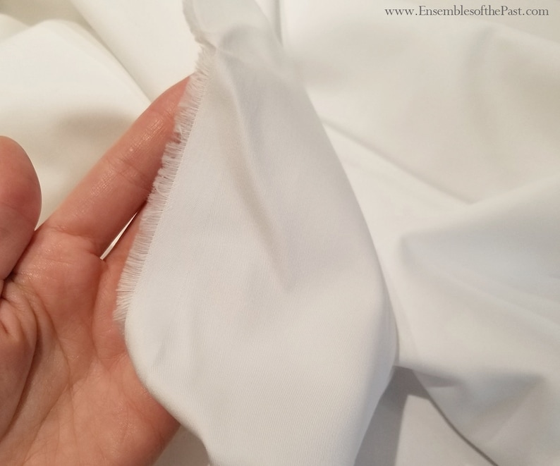 May include: Close-up of white cotton fabric with a raw edge. The fabric is smooth and has a slight sheen.