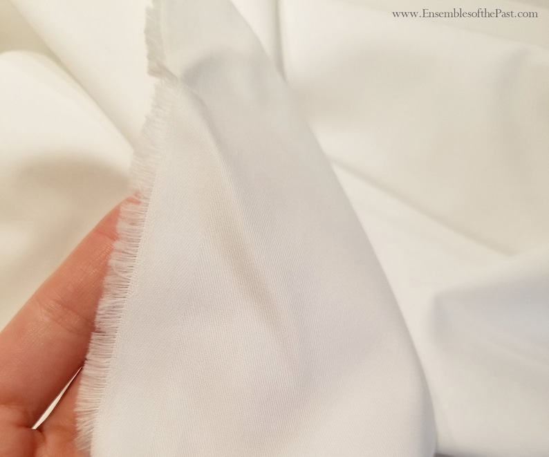 May include: Close-up of white fabric with a slightly textured surface. The fabric has a raw edge.