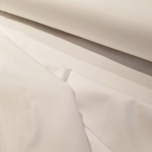 May include: White fabric, folded and rolled, showing the smooth texture and soft drape of the material.