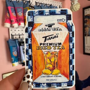 Könnte beinhalten: Ein Aufkleber mit einer Illustration im Vintage-Stil eines Kartons mit Turner's Premium Eistee. Das Design zeigt ein Glas Eistee mit Zitronen und den Text "Premium Iced Tea". Der Aufkleber ist etwa ein Pint (473 ml).