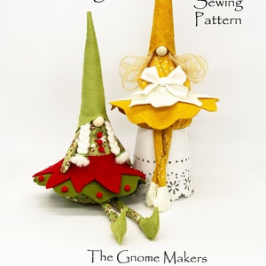 Könnte beinhalten: Nähmuster für zwei Gnome, einer mit gelbem Hut und Kleid und der andere mit grünem Hut und rotem Kleid. Das Muster trägt den Titel "Darling Designs!" und "The Gnome Makers".