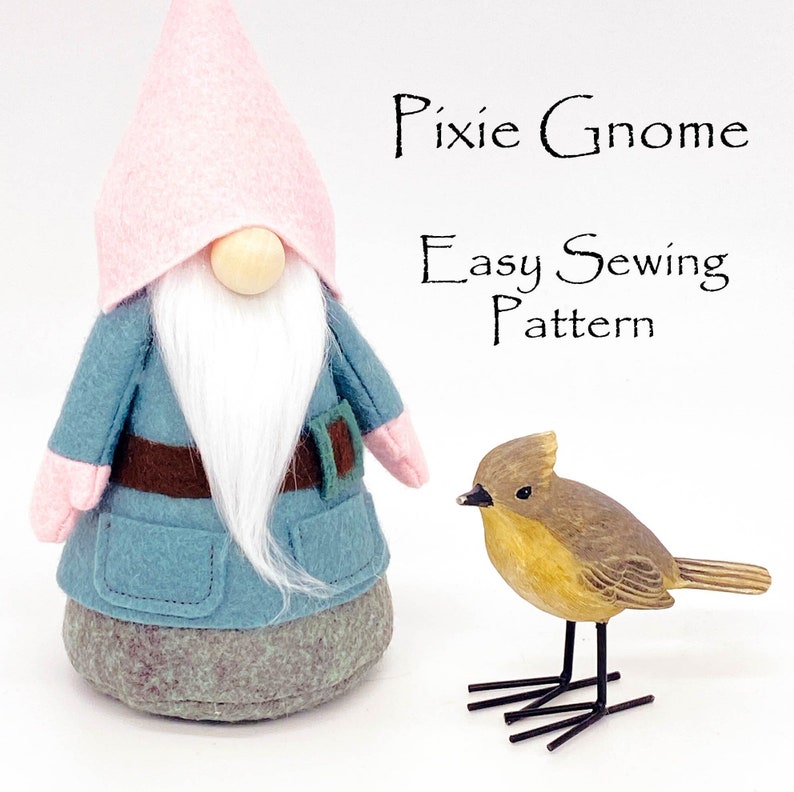 K&ouml;nnte beinhalten: Ein blauer und rosa Filz-Zwerg mit wei&szlig;em Bart und braunem G&uuml;rtel. Der Zwerg steht neben einem kleinen Holzvogel mit schwarzen Drahtbeinen. Der Text "Pixie Gnome Easy Sewing Pattern" steht &uuml;ber dem Zwerg.
