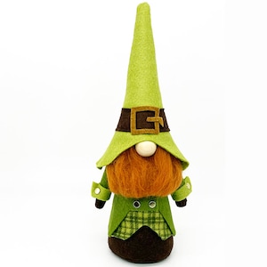 May include: A green felt gnome with a brown belt and a green hat. The gnome has a brown felt beard and a brown felt body.
