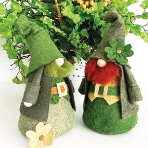 May include: Two green felt gnome figurines with red and green accents. One gnome has a green hat with a shamrock and the other has a green hat with a yellow flower.